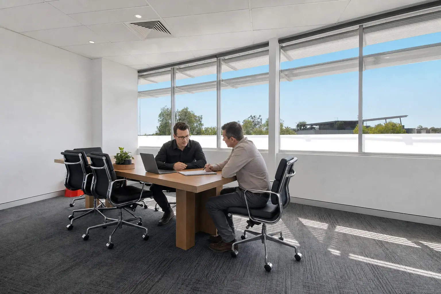 Matt reviewing campaign strategy with a small-business client in a Robina meeting room
